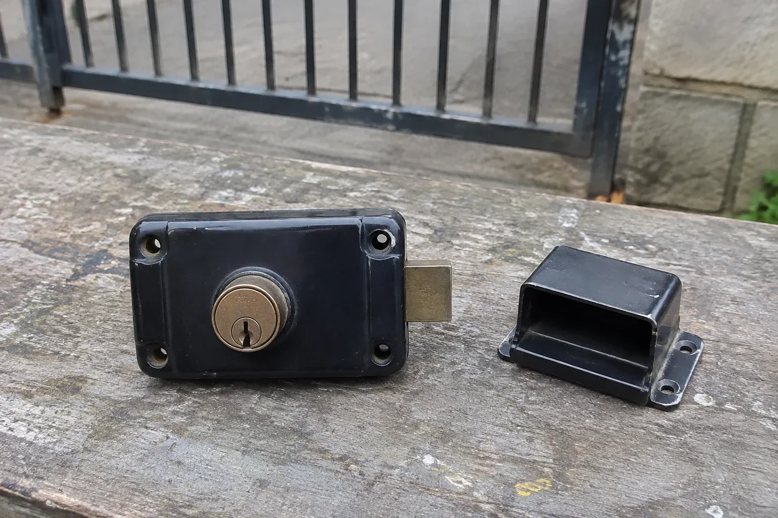 Detached rim gate lock and separate box keeper on an outdoor workbench. — Gate & Building Entry Locks, Vaughan