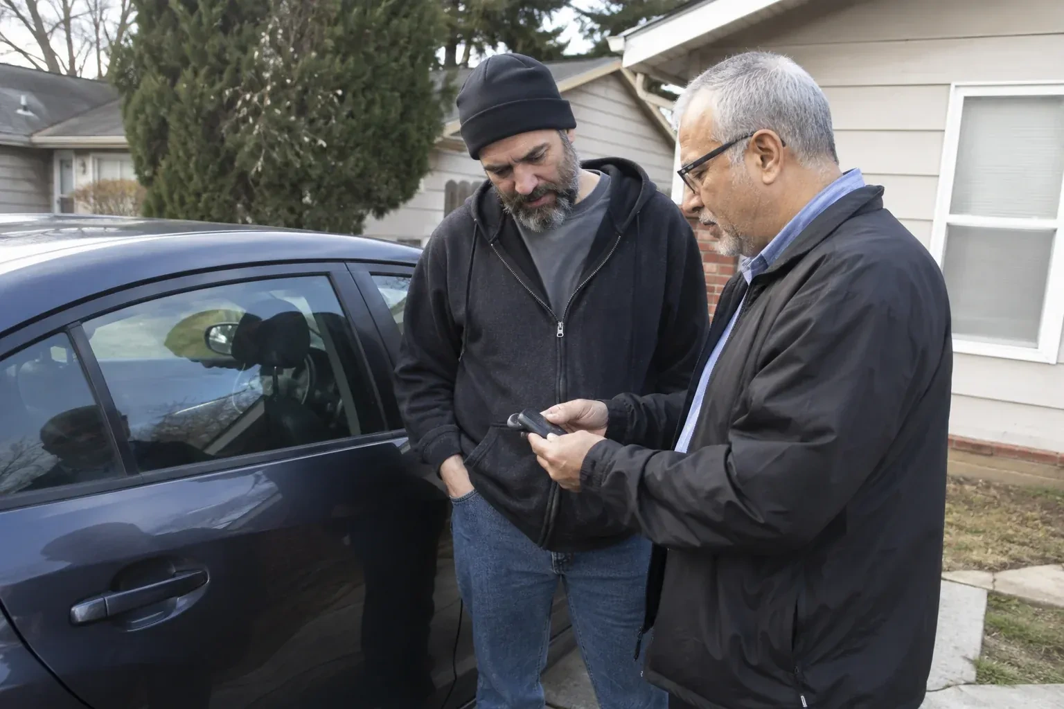 Two adults discussing a key fob beside a parked car. — Car Lockout Service, Vaughan